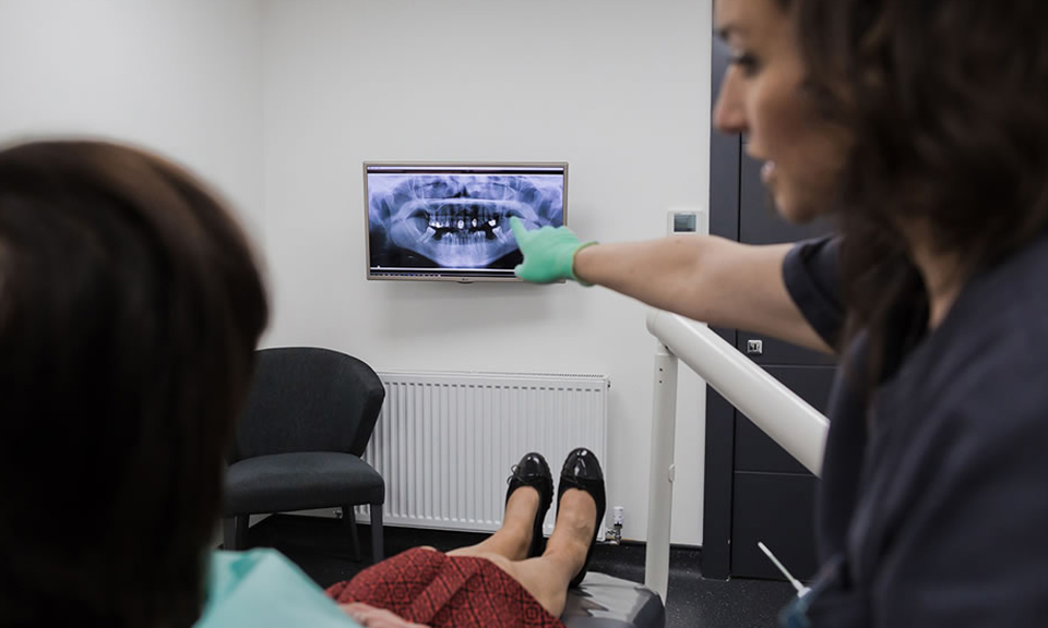 Dentist showing a patient their dental X-ray on a wall screen